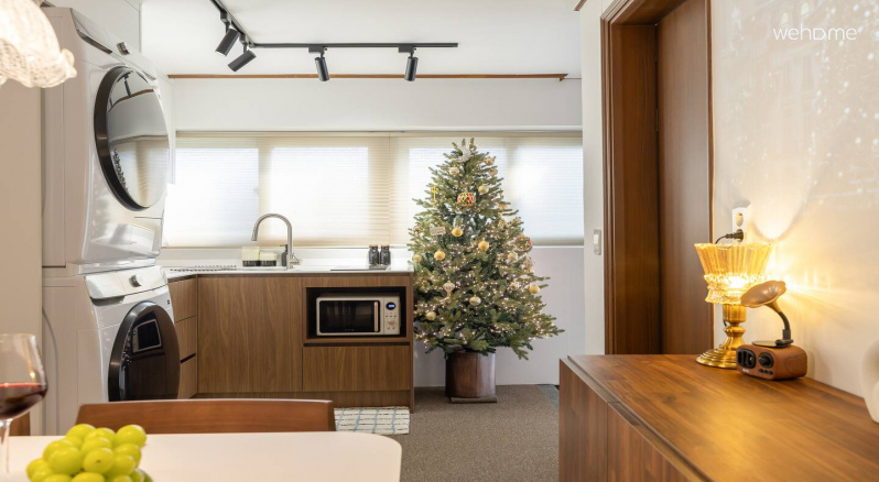 주방 싱크대 옆, 현관 앞에 트리가 놓여 있어 공간에 따뜻한 분위기를 더해줍니다. 일상적인 주방 공간에 계절의 감성이 자연스럽게 스며들어 있습니다.