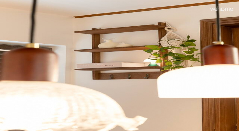 따뜻한 빛의 앤틱 조명과 그 뒤로 보이는 월넛 선반, 그리고 감각적인 오브제가 어우러져 공간에 자연스러운 고급스러움을 더합니다. 작은 디테일 하나까지 분위기를 생각한 장면입니다.