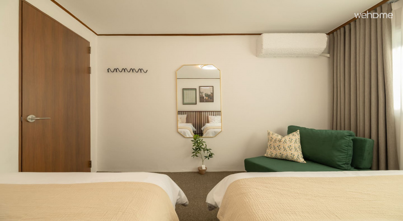 침대, 녹색 소파, 벽 거울이 있는 1호실. 편안한 휴식을 상상하게 만드는 따뜻한 공간입니다.
Room 1 with a bed, green couch, and wall mirror. It's a warm space that makes you imagine a comfortable rest.
