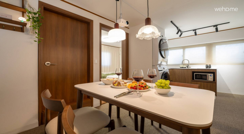 다이닝 공간 뒤로 주방이 이어져 있어 공간이 자연스럽게 연결되어 있습니다.
식탁 조명의 부드러운 빛 아래에서 식사를 즐기고, 바로 이어진 주방에서 간단한 요리나 티타임을 준비하기에도 편리해요. 함께 머무는 시간이 더 가까워지는 구조입니다.
