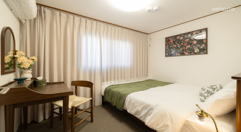 월넛 가구의 깊은 색감 위로 그린 톤의 룸2! 꽃 사진과 화병이 자연스러운 포인트가 되어 공간에 생기를 더합니다. 차분함과 따뜻함이 가득한 침실입니다!