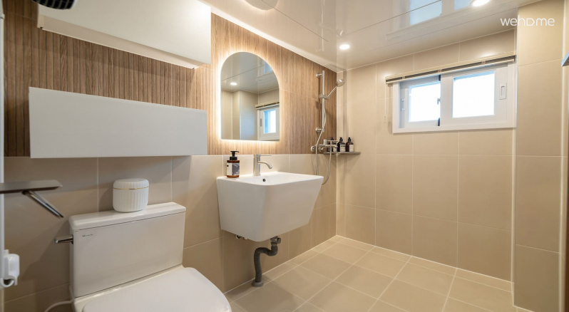 우드 톤으로 꾸며진 욕실에 거울 뒤 조명이 더해져 부드럽고 안정감 있는 분위기를 만들어줍니다.Wood-toned bathrooms are added with lighting behind the mirror to create a soft and stable atmosphere.